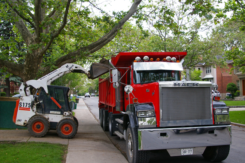 Skid steer loading excavated material into a truck